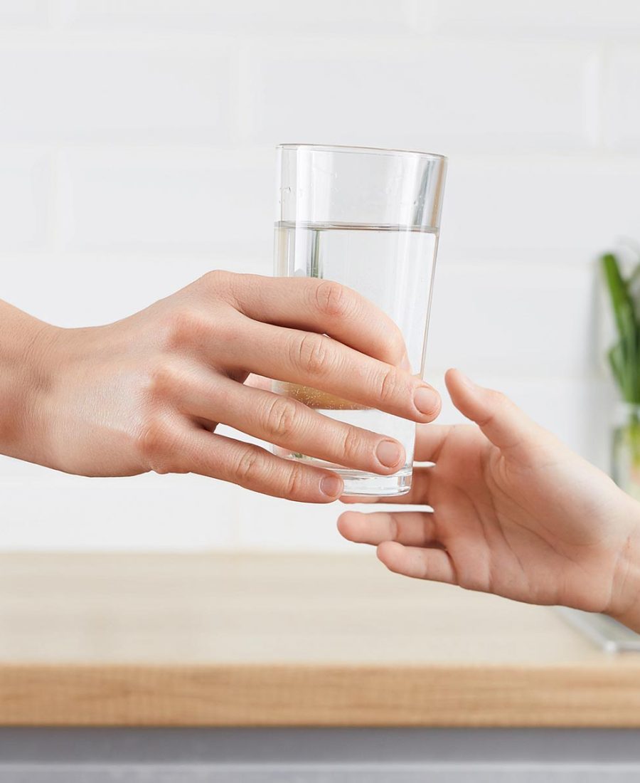 woman's hand gives a glass of purified water to her child. Concept purification of water